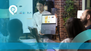 Seorang profesional wanita sedang mempresentasikan data performa melalui laptop kepada tim dalam sebuah rapat, menunjukkan grafik analisis dan statistik keberhasilan kampanye digital marketing.