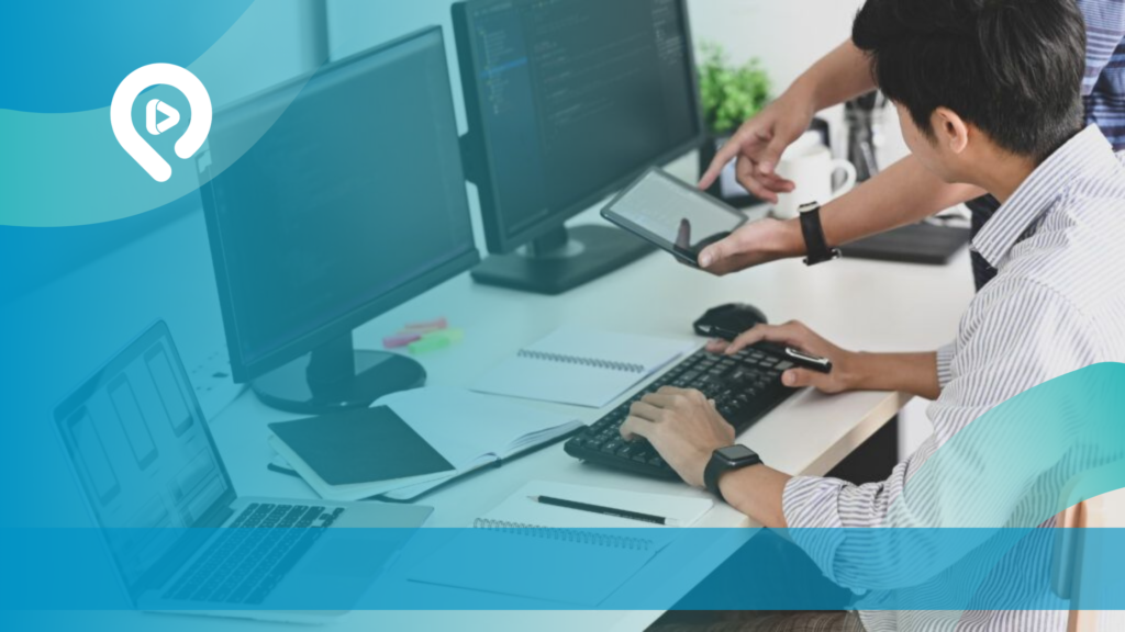 Seorang pria bekerja menggunakan komputer desktop dan laptop di meja kerja dengan perangkat digital untuk mendukung pengembangan website.